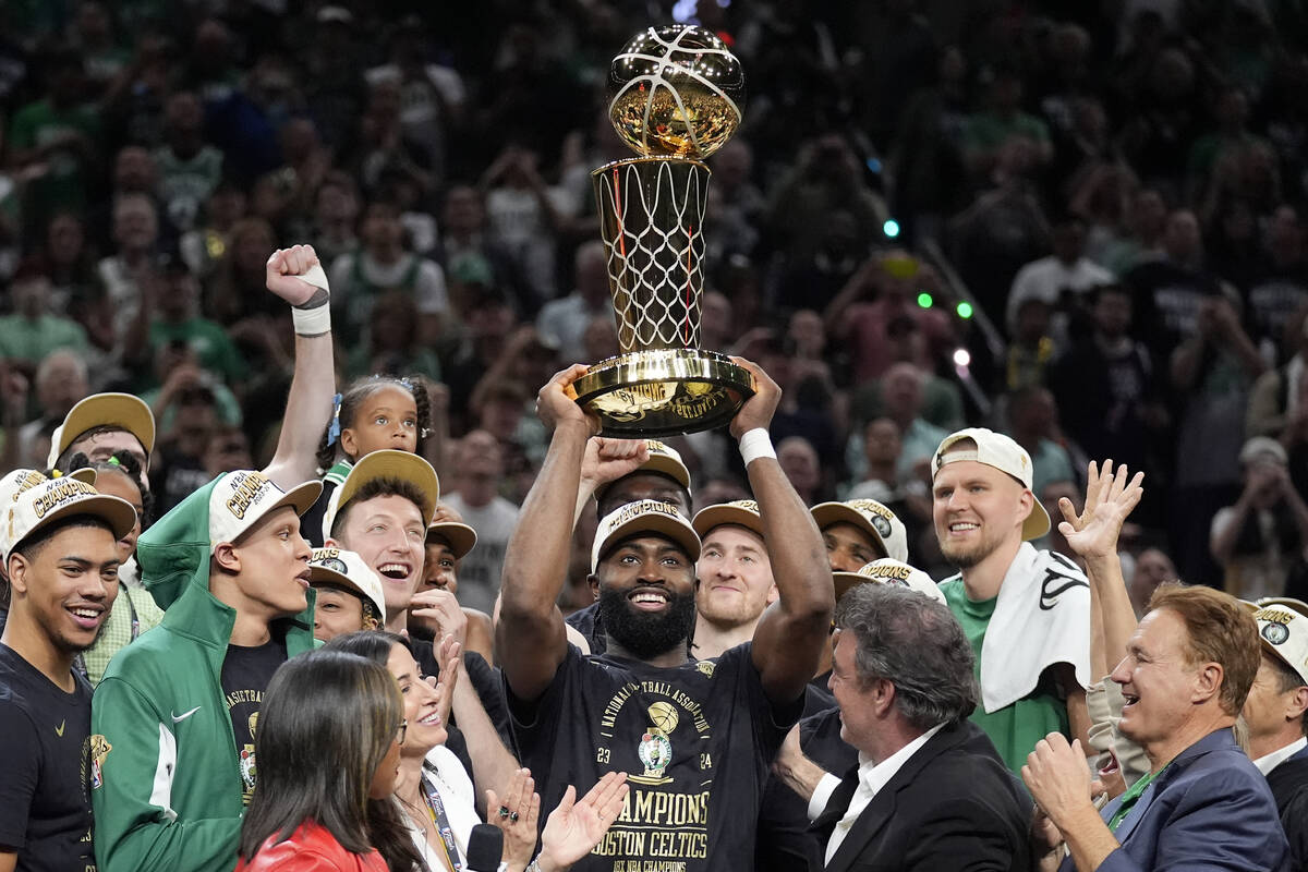 Boston Celtics guard Jaylen Brown, center, holds up the Larry O'Brien Championship Trophy as he ...
