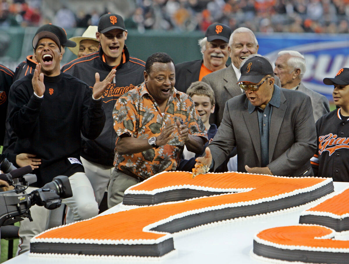 FILE - Willie Mays, right, uses his hand to chop through a large birthday cake presented in hon ...