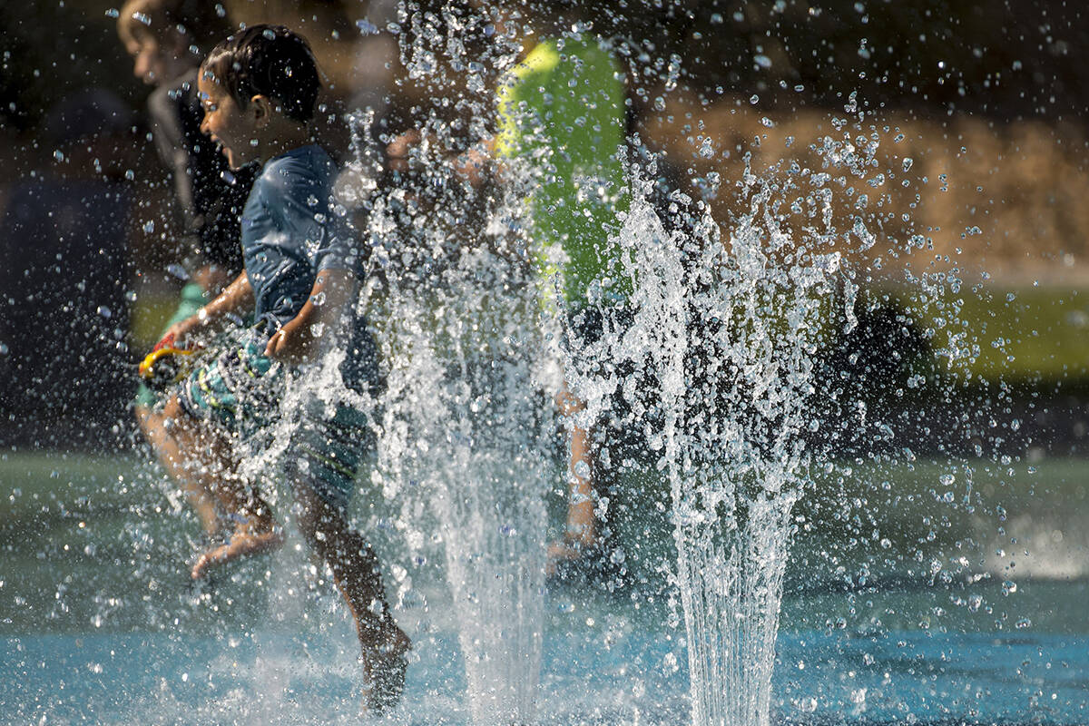 Leo Reyes, 3, runs through the water fountains as he stays cool on the splash pad at The Paseos ...