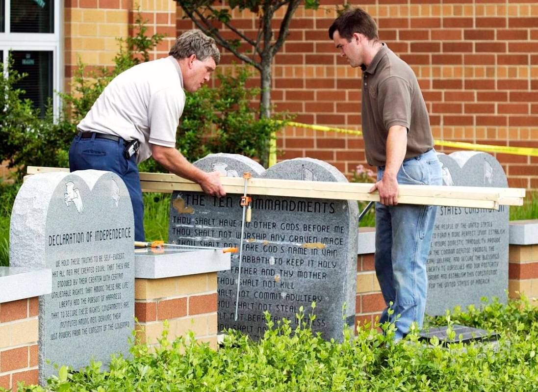 Workers remove a monument bearing the Ten Commandments outside West Union High School, Monday, ...