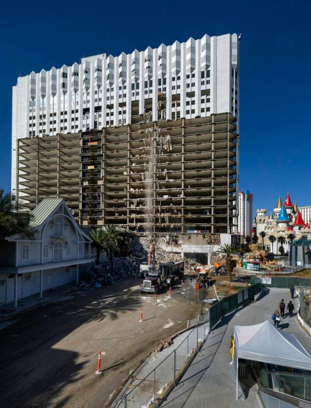 Debris is pushed out of a higher floor to a pile below for transport as demolition continues on ...