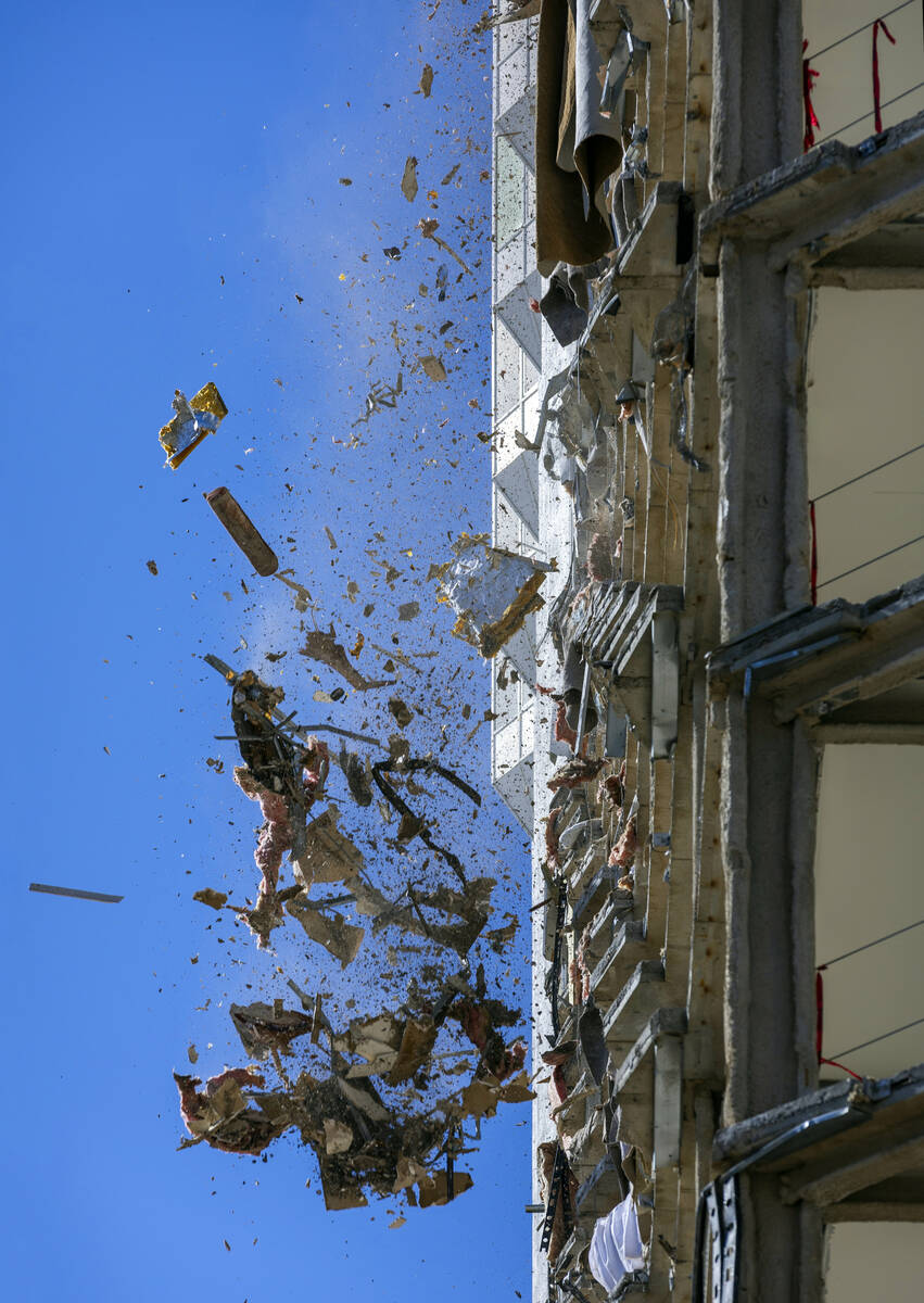 Debris is pushed out of a floor above to a pile below for transport as demolition continues on ...