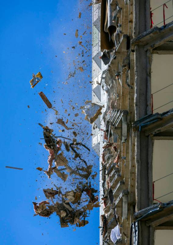 Debris is pushed out of a floor above to a pile below for transport as demolition continues on ...