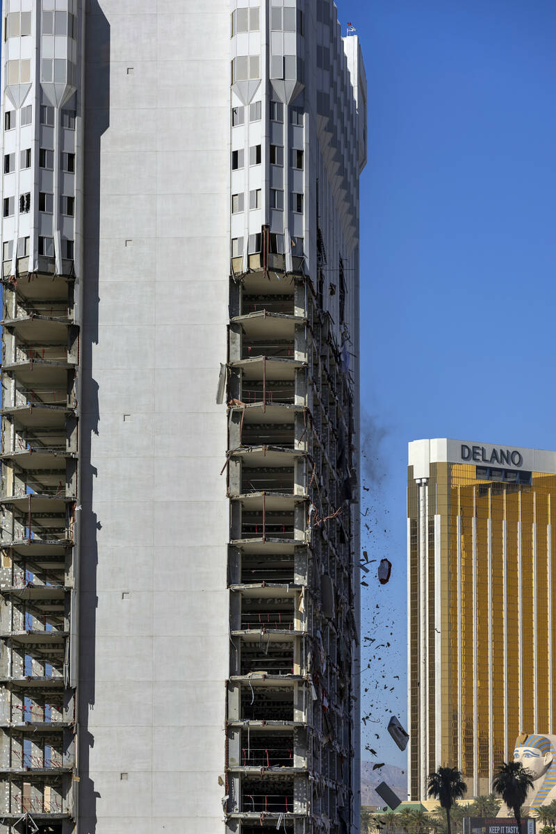 Debris is pushed out of a higher floor to a pile below for transport as demolition continues on ...