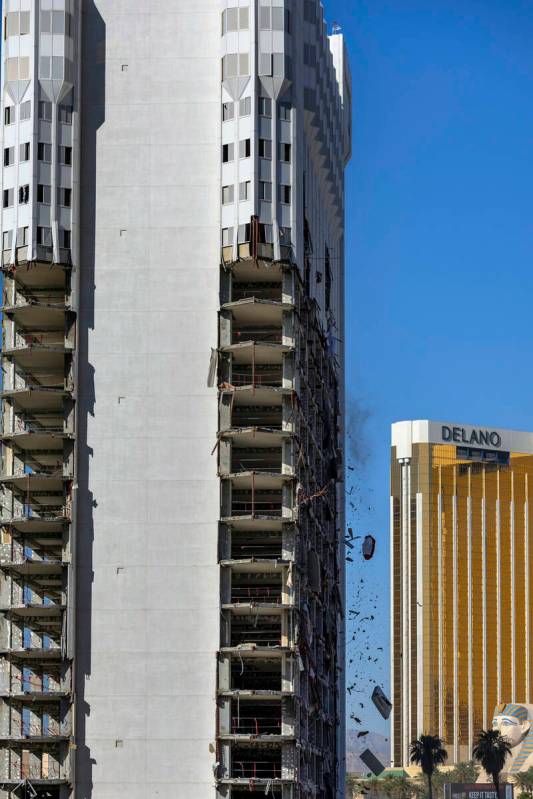 Debris is pushed out of a higher floor to a pile below for transport as demolition continues on ...