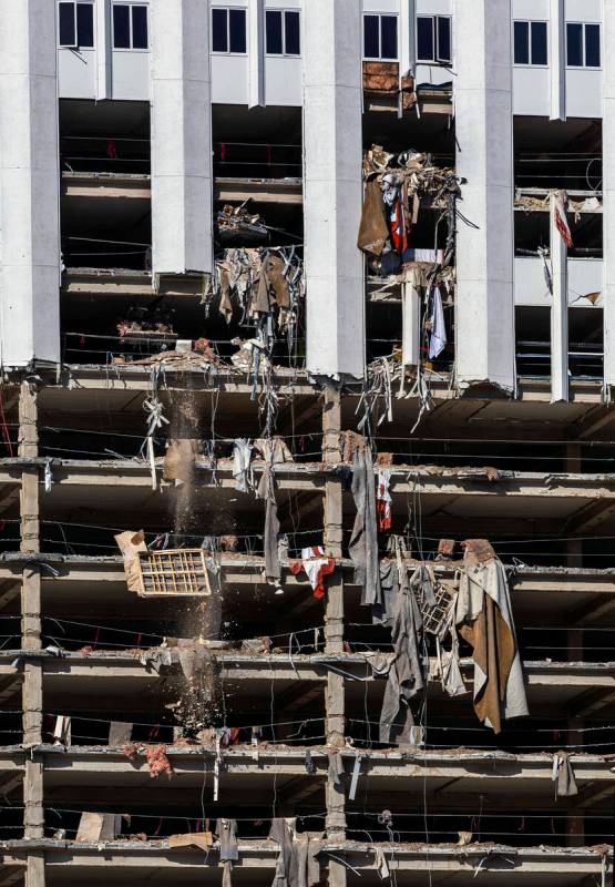 Debris including an old box spring is pushed out of a higher floor to a pile below for transpor ...