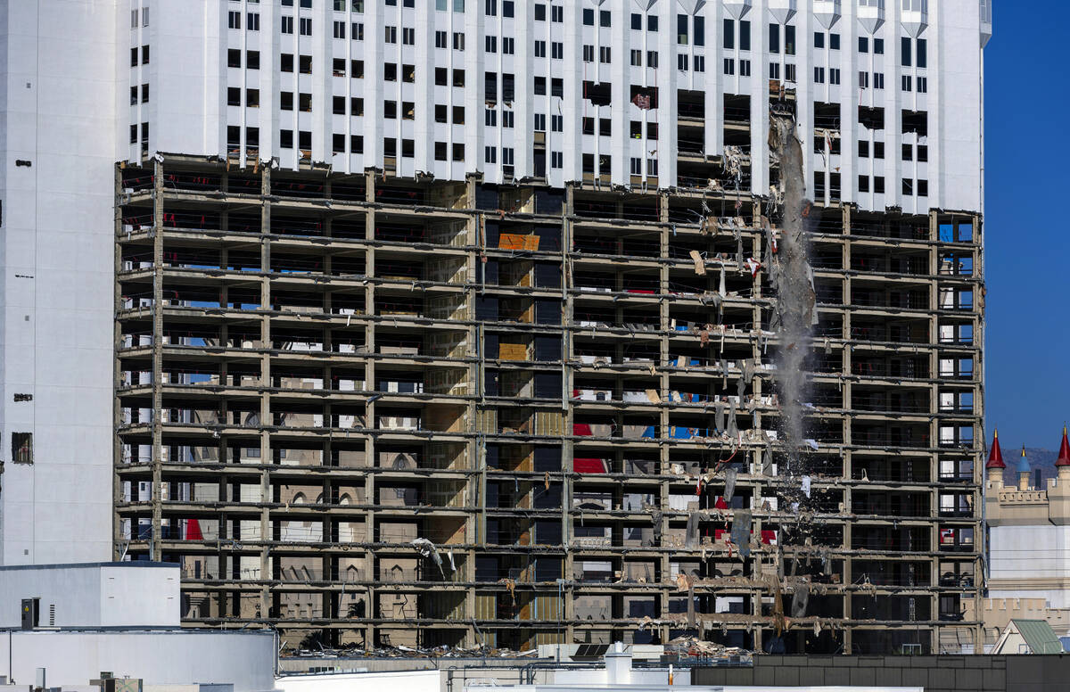 Debris is pushed out of a higher floor to a pile below for transport as demolition continues on ...