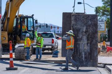 A construction worker drinks water on a road project along West Charleston Blvd. as he and othe ...