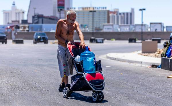 A homeless man wheels a jug of water to his encampment along about E. Washington Ave. on Wednes ...