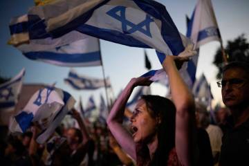 People wave Israeli flags during a protest against Israeli Prime Minister Benjamin Netanyahu's ...
