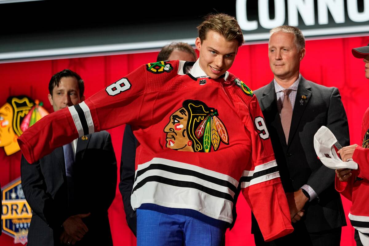 Chicago Blackhawks first round draft pick Connor Bedard puts on his jersey after being picked b ...