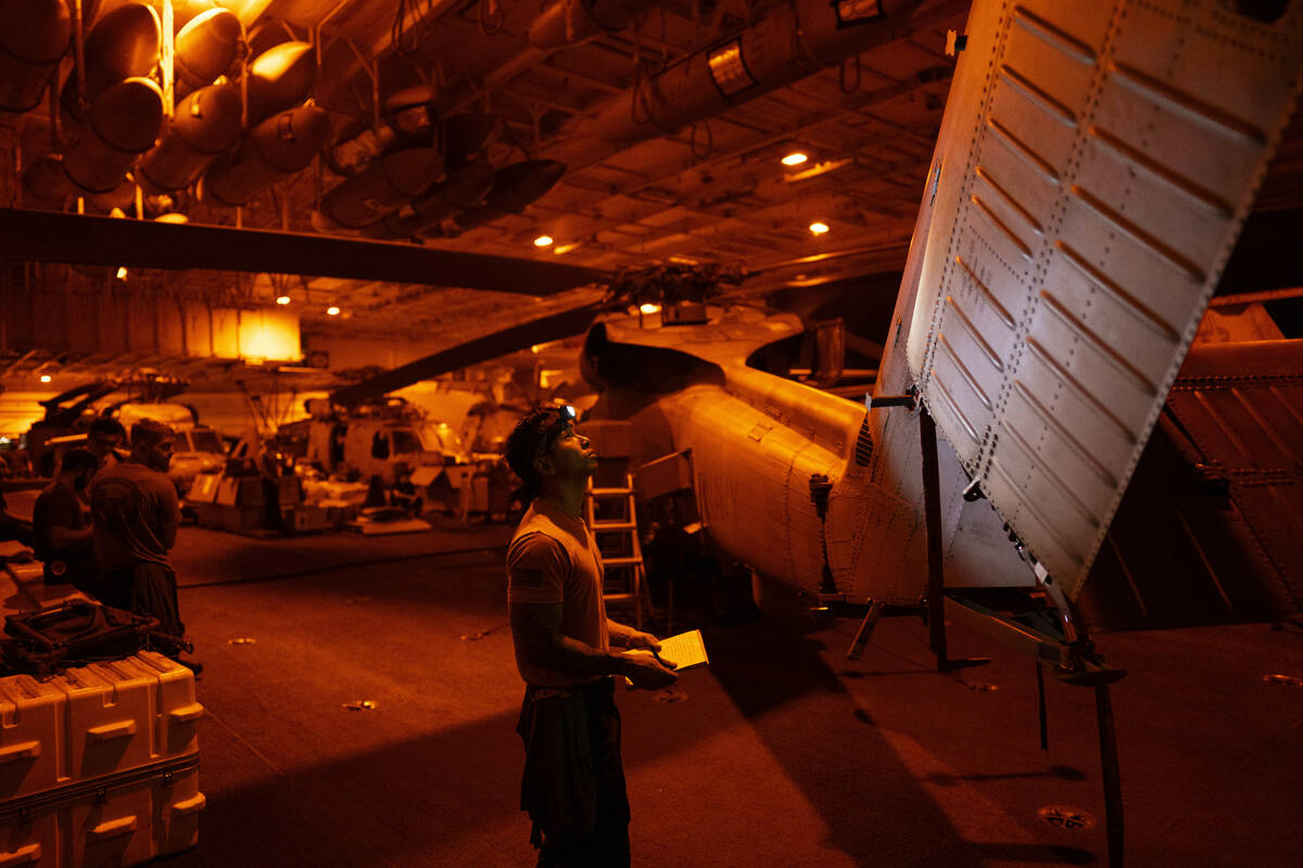 A crew member checks a helicopter in the hangar bay of the USS Dwight D. Eisenhower in the Red ...