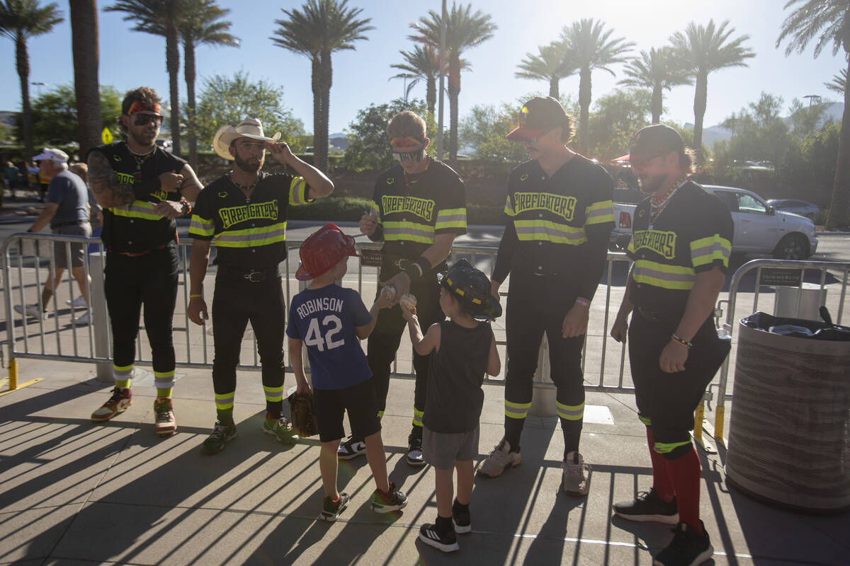 Young fans have baseballs signed by members of the Firefighters before the game against the Par ...