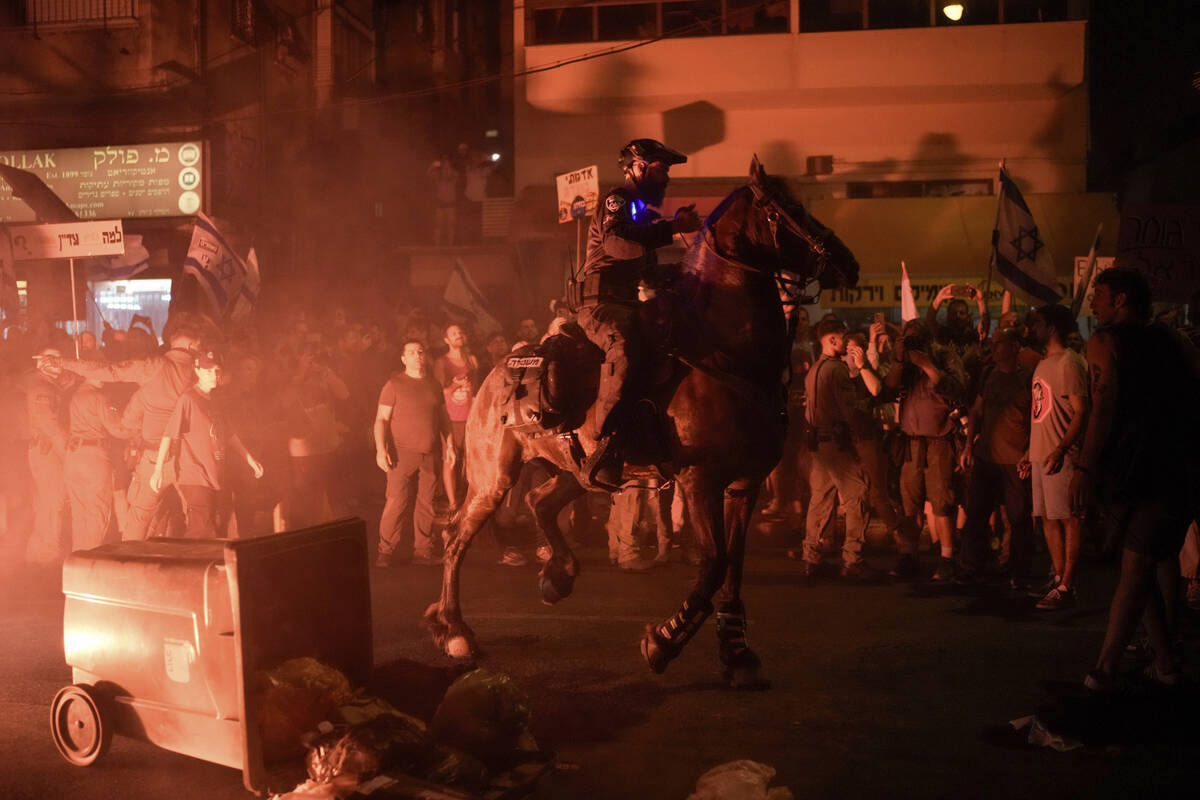 Israeli mounted police officers disperse demonstrators blocking a road during a protest against ...