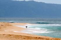 A surfer walks out of the ocean on Oahu's North Shore near Haleiwa, Hawaii, March 31, 2020. Aut ...