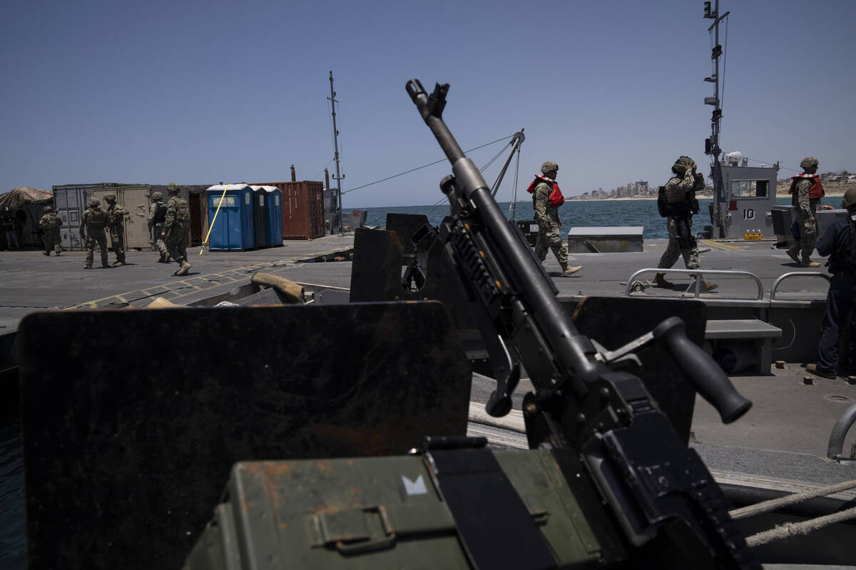 U.S. Army soldiers stand at the U.S.-built floating pier Trident backdropped by the coast of th ...