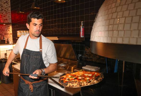 World champion pizza maker Michael Vakneen pulls a pizza from the oven at Double Zero Pie & Pub ...