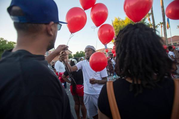 Red balloons are handed out during a candlelight service for Kayla Harris at Craig Ranch Villas ...
