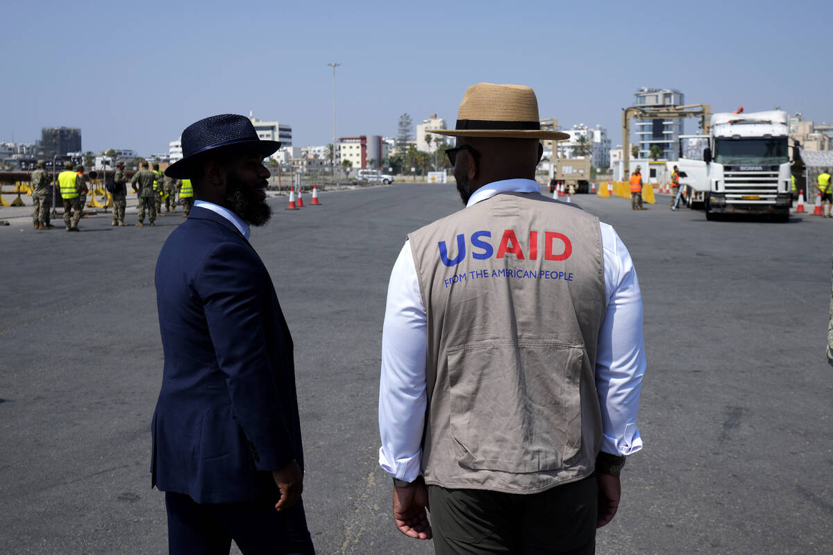 Members staff of U.S Aid stand as Gaza aid on a truck is about to enter a U.S ship, at the port ...