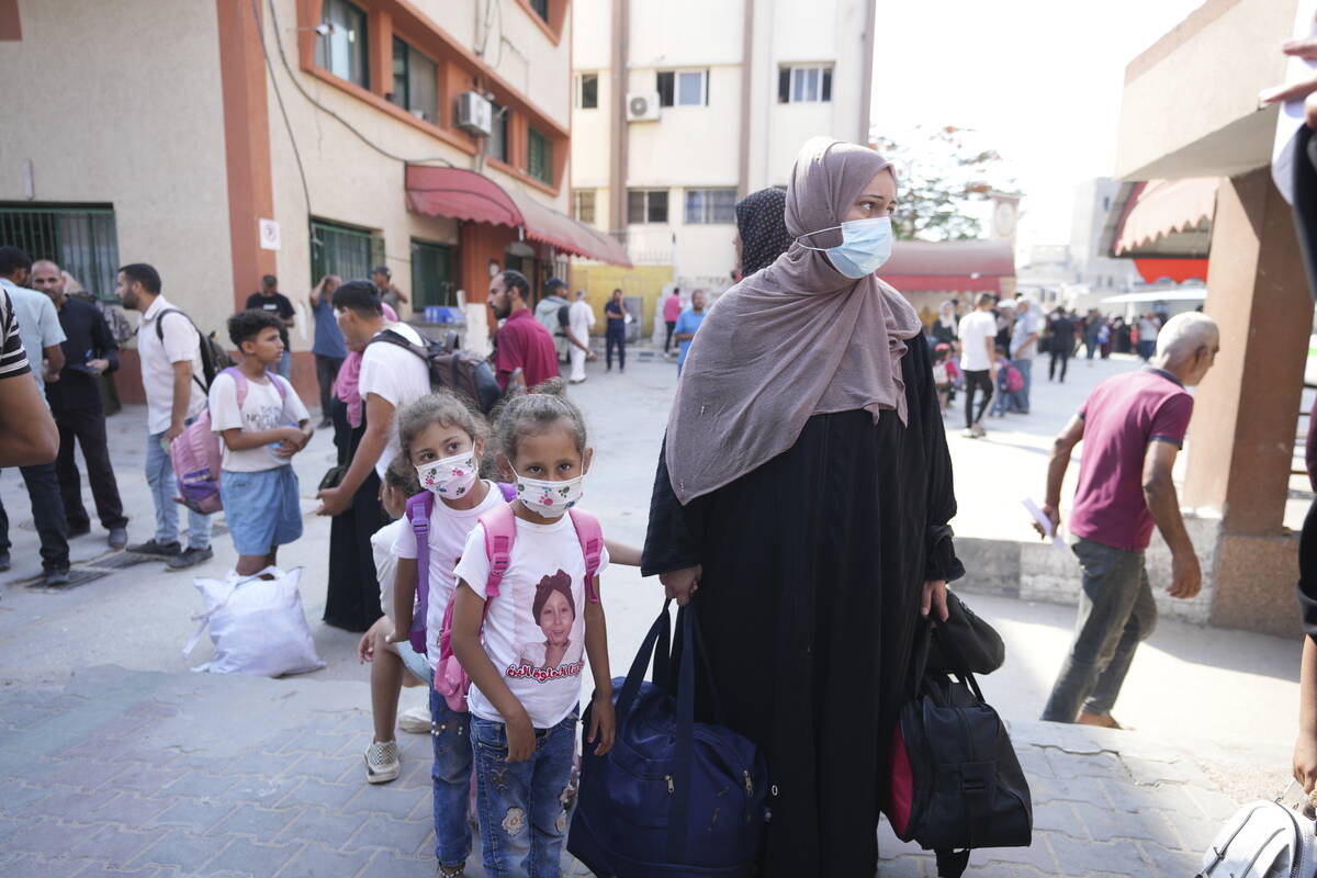 Palestinian children with chronic diseases stand next to their mother as they wait to leave the ...