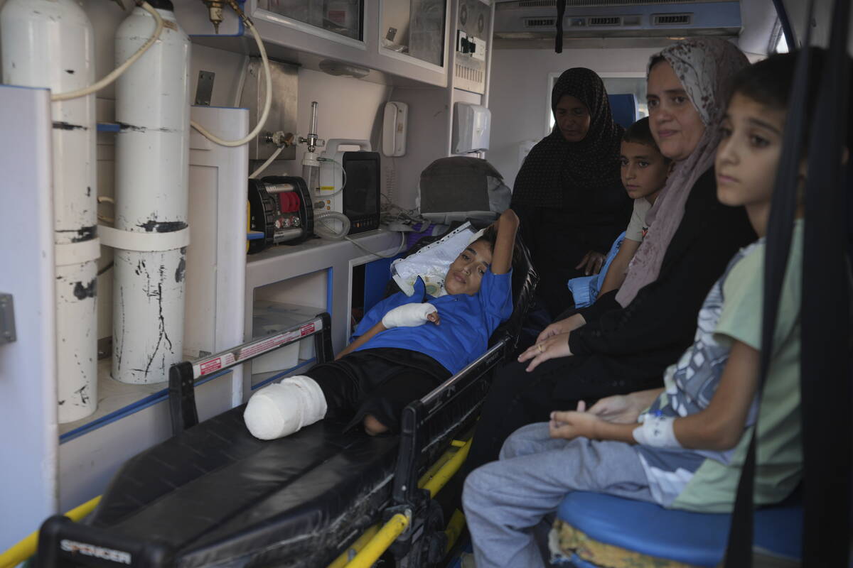 An amputee Palestinian child sits in an ambulance with his relatives as he waits to leave the G ...