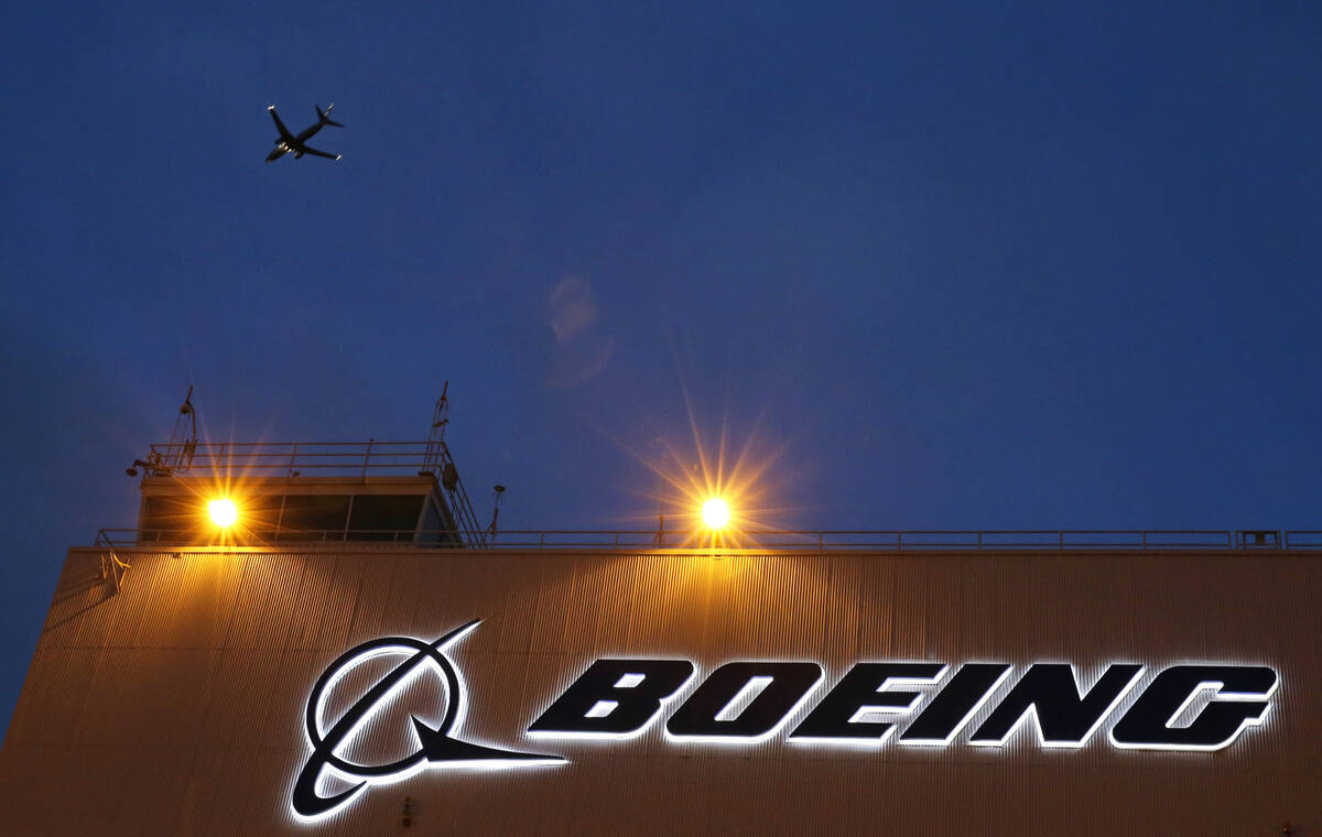 An airplane flies over a sign on Boeing's newly expanded 737 delivery center, Oct. 19, 2015, at ...