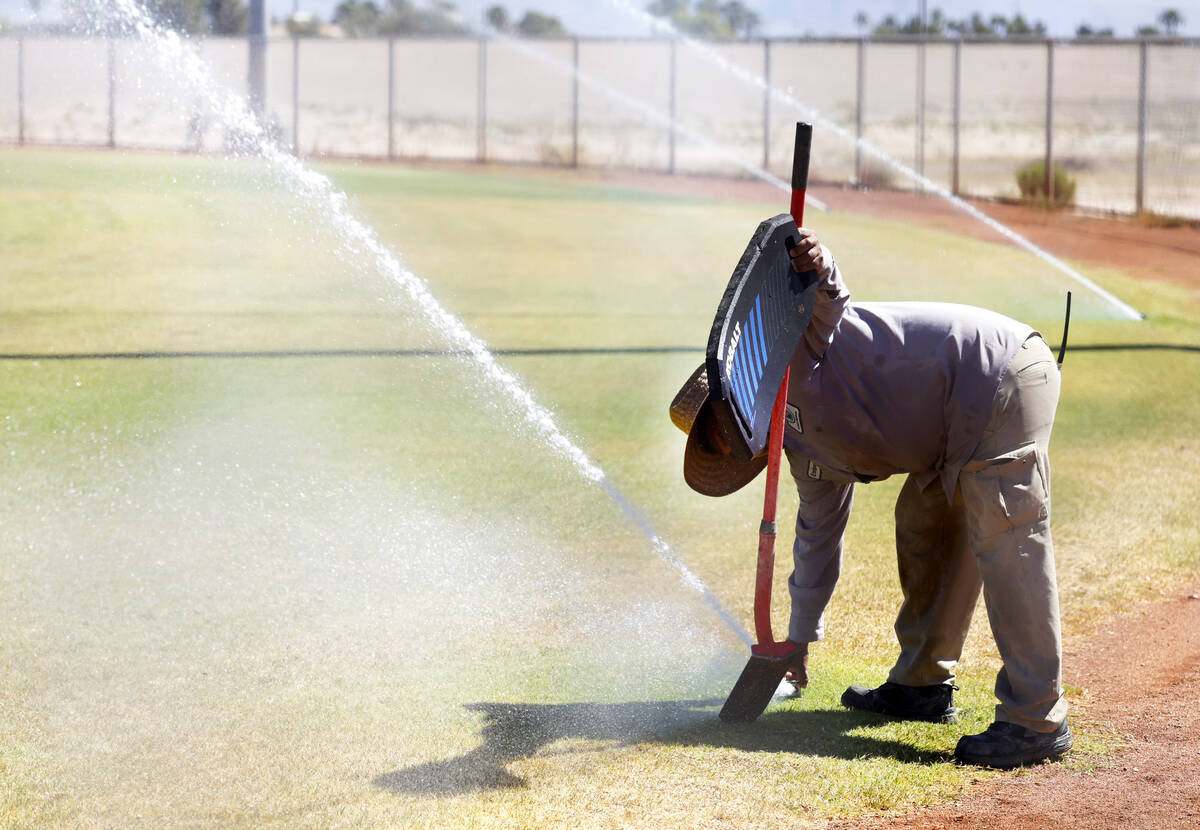 Martinez Enrique, a groundkeeper at Doc Romeo baseball park, inspects sprinklers during a hot d ...