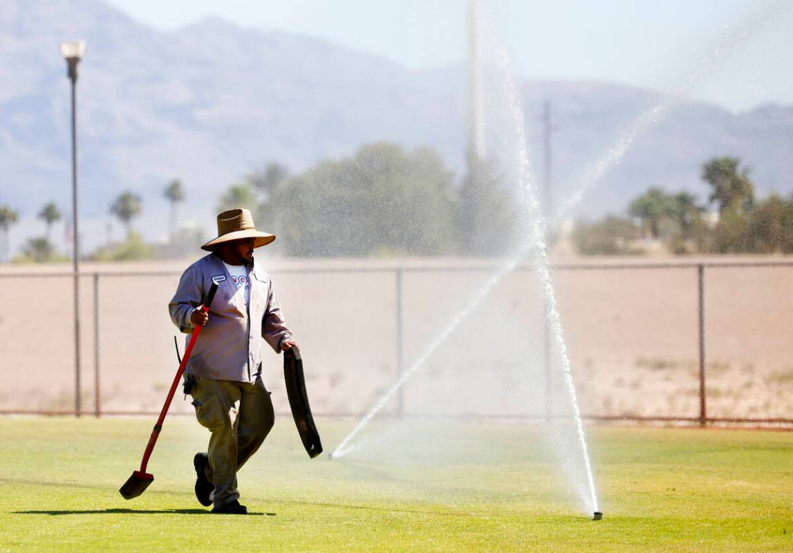 Martinez Enrique, a groundkeeper at Doc Romeo baseball park, inspects sprinklers during a hot d ...