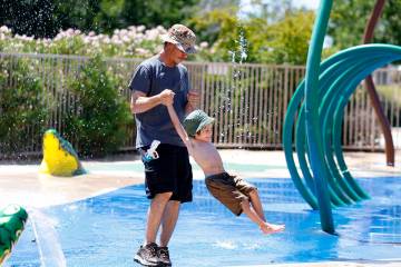 Seth Williams of Las Vegas plays in the splash pad with his sons Ambrose, 2, at Aliante Nature ...