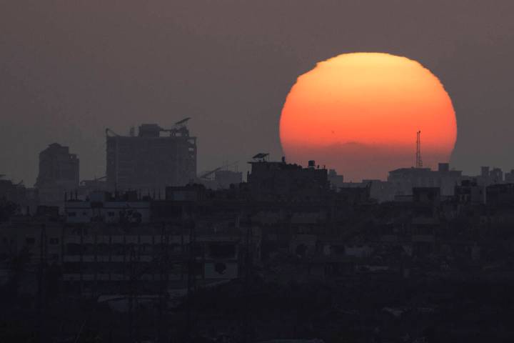 The sun sets behind the buildings in the Gaza Strip as seen from southern Israel, Saturday, Jun ...