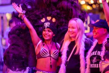 Tourists take photographs with a couple of showgirls at the Fremont Street Experience Monday, J ...