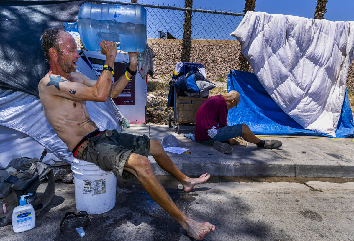 FILE - Homeless man Milton John Scott III pours a jug of water on his head to escape the heat a ...