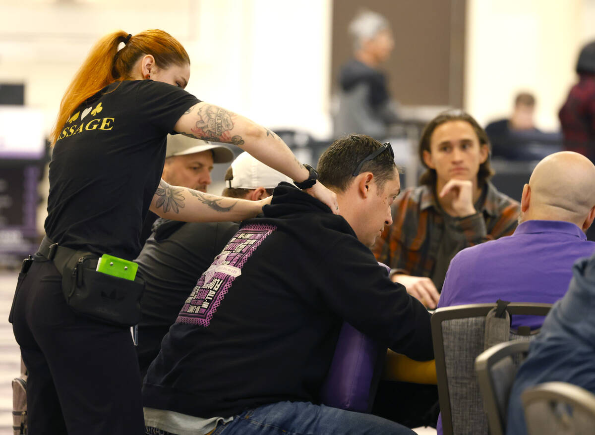 A massage therapist gives a poker player a massage during the first day of the World Series of ...