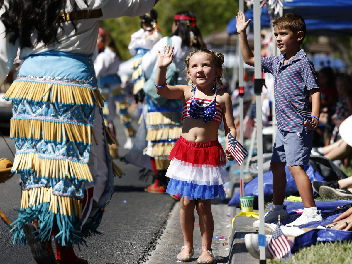 Scarlett Legrow, center, and Carsen Moakler, right, wave as they watche the annual Summerlin Co ...