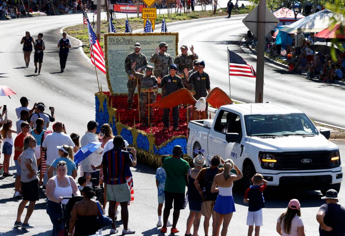 Members of the military wave to the crowd from the All-Star Salute to the Military float during ...