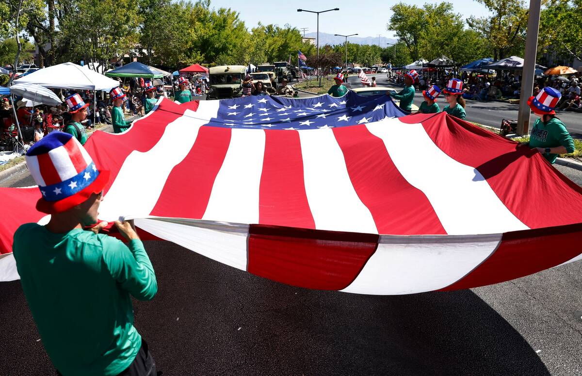 Nick Meis, left, Palo Verde cross country men's head coach, and students wave a giant American ...