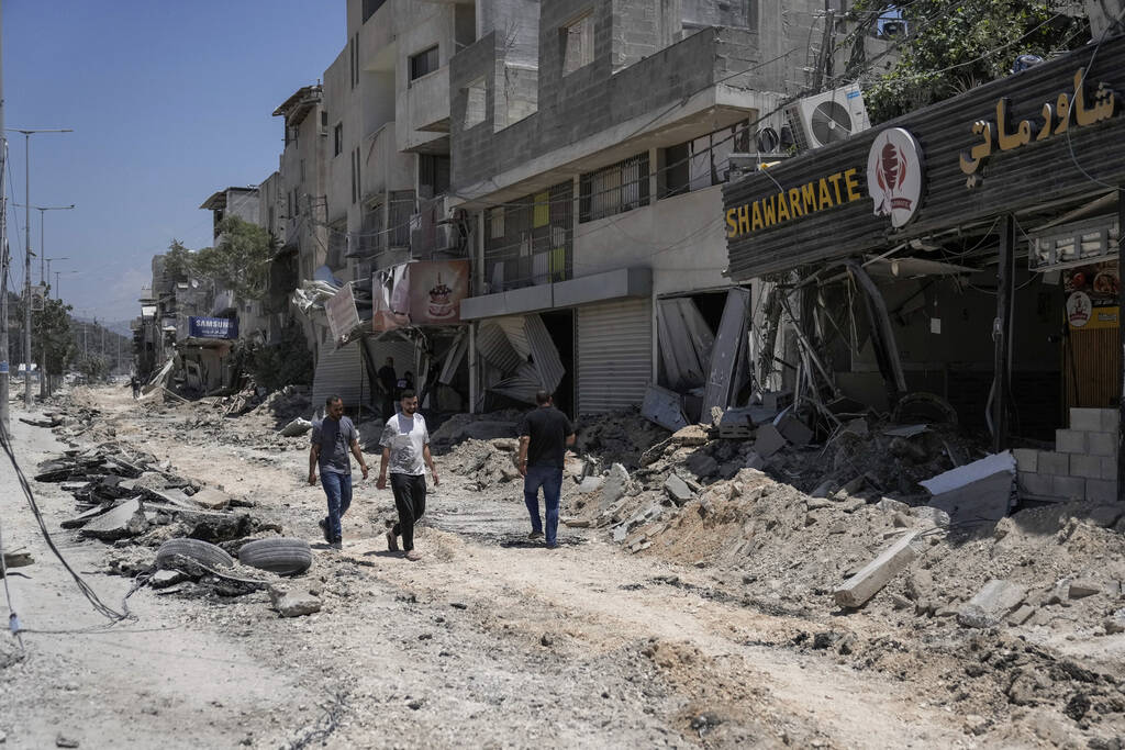 Palestinians walk along a damaged road following an Israeli operation in Nur Shams refugee camp ...