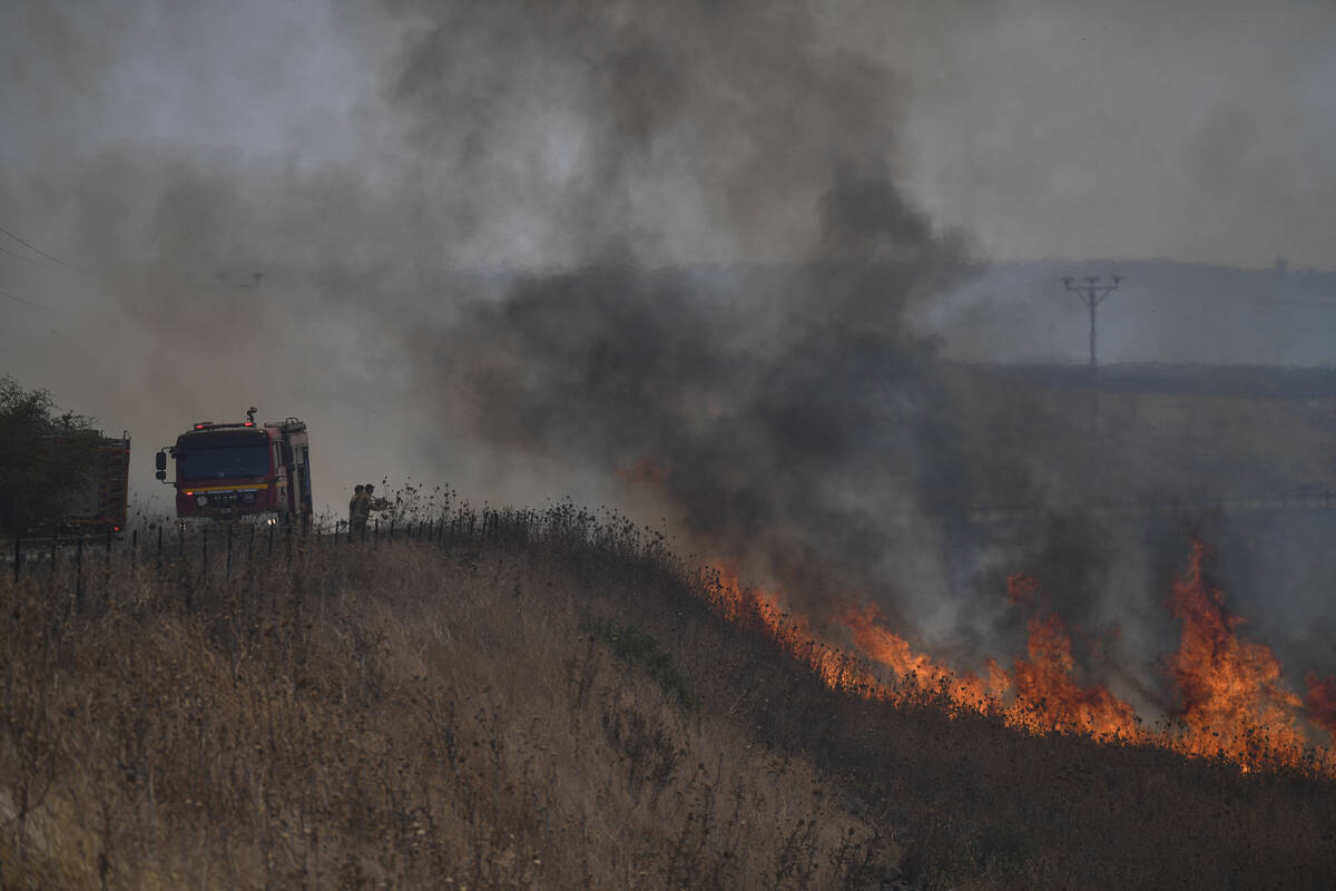 Firefighters work to extinguish a fire following an attack from Lebanese Hezbollah group, in an ...