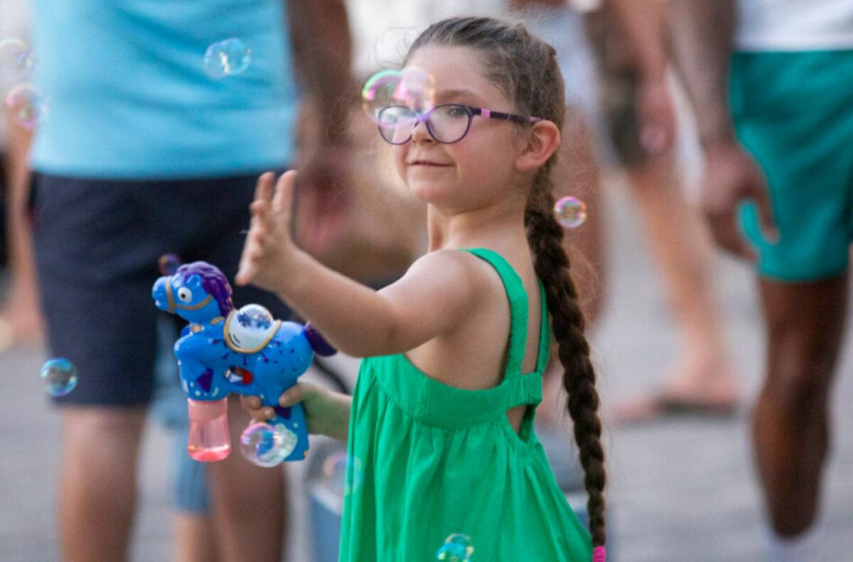 A girl plays with a bubble machine during the Independence Day celebration at Lake Las Vegas Th ...