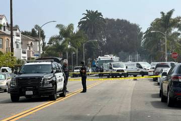 Police officers stand guard at the crime scene where police say two people were killed and thre ...