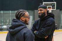 Los Angeles Lakers draft pick Bronny James, left, and his father, LeBron James, share a light m ...
