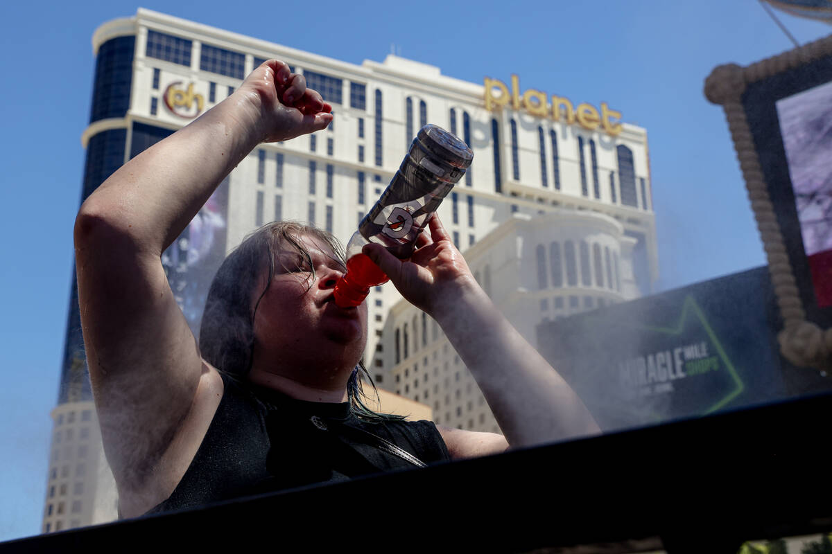 Laney Athon, of Cincinnati, drinks Gatorade as she cools off in front of misters outside Paris ...