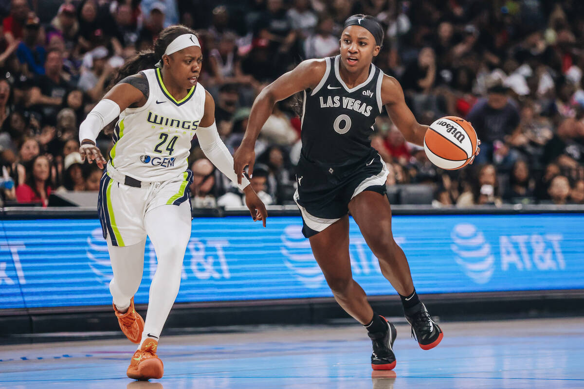 Aces guard Jackie Young (0) dribbles the ball as Dallas Wings guard Arike Ogunbowale (24) guard ...