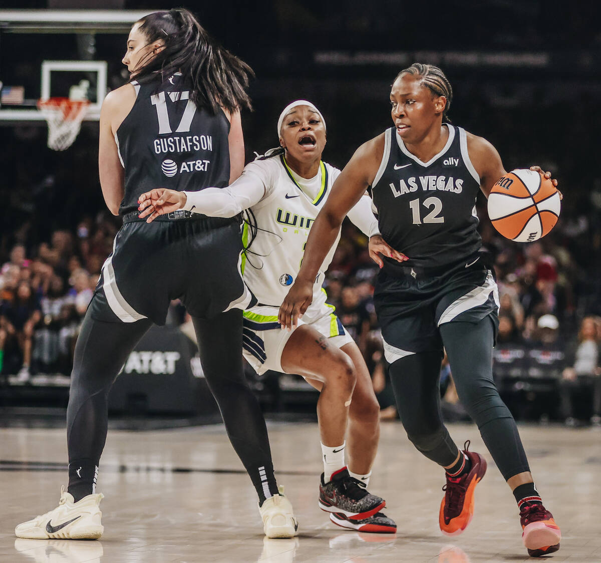 Aces guard Chelsea Gray (12) dribbles the ball as Dallas Wings guard Odyssey Sims (2) tries to ...