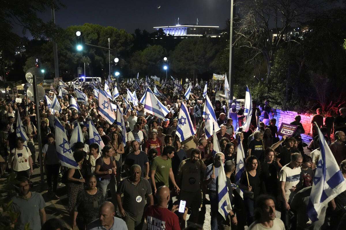 Demonstrators march with Israeli flags during a protest marking nine months since the start of ...