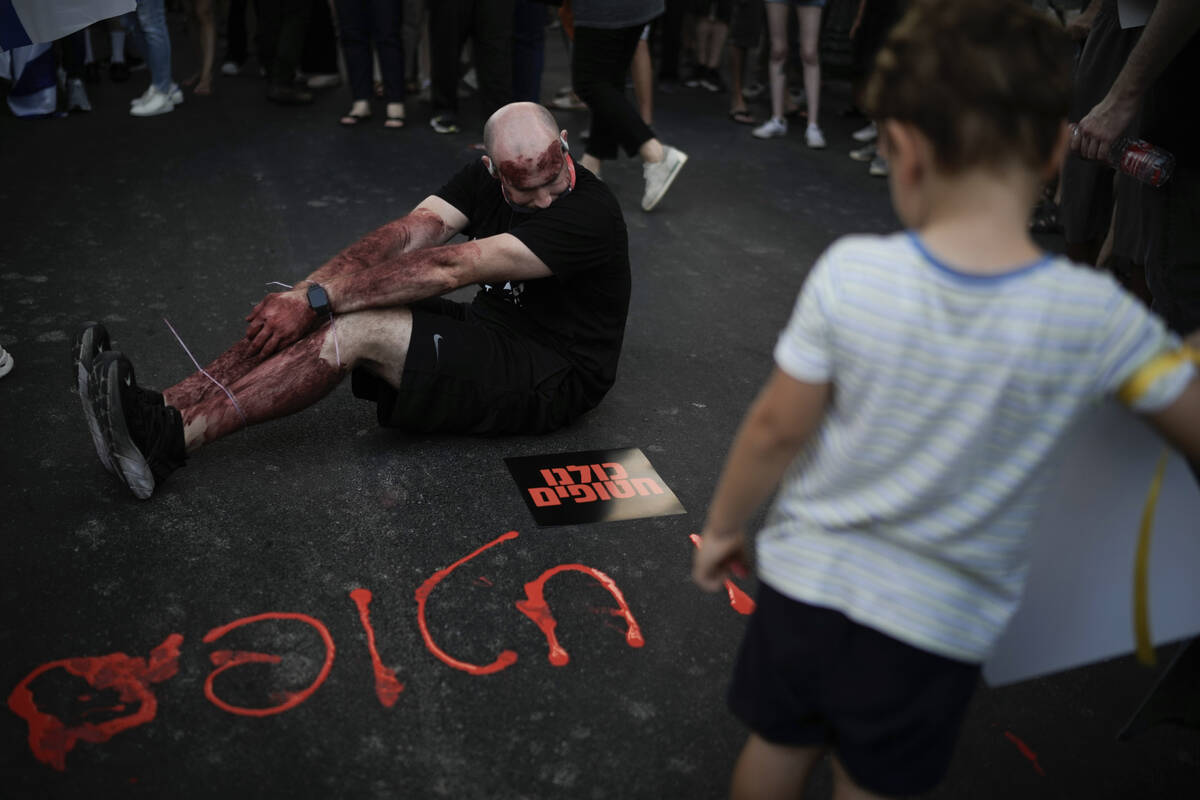 A man painted in red to symbolize blood during a protest marking nine months since the start of ...