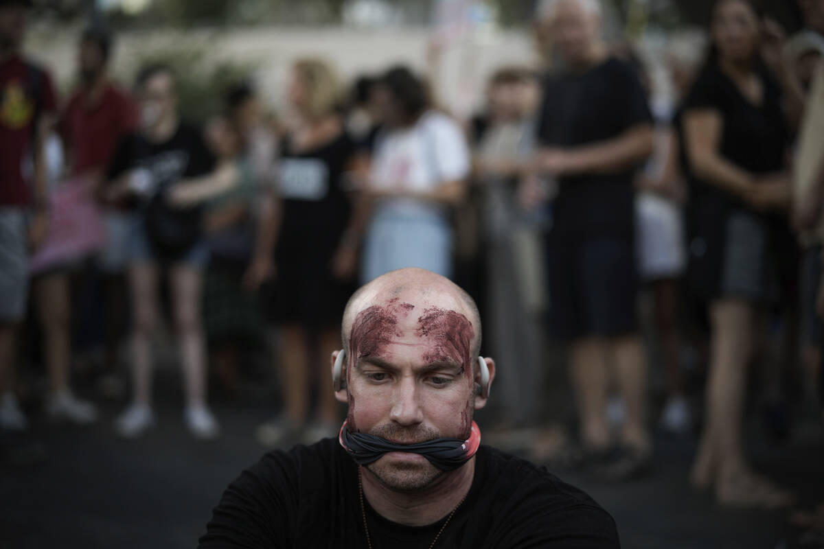 A man painted in red to symbolize blood during a protest marking nine months since the start of ...