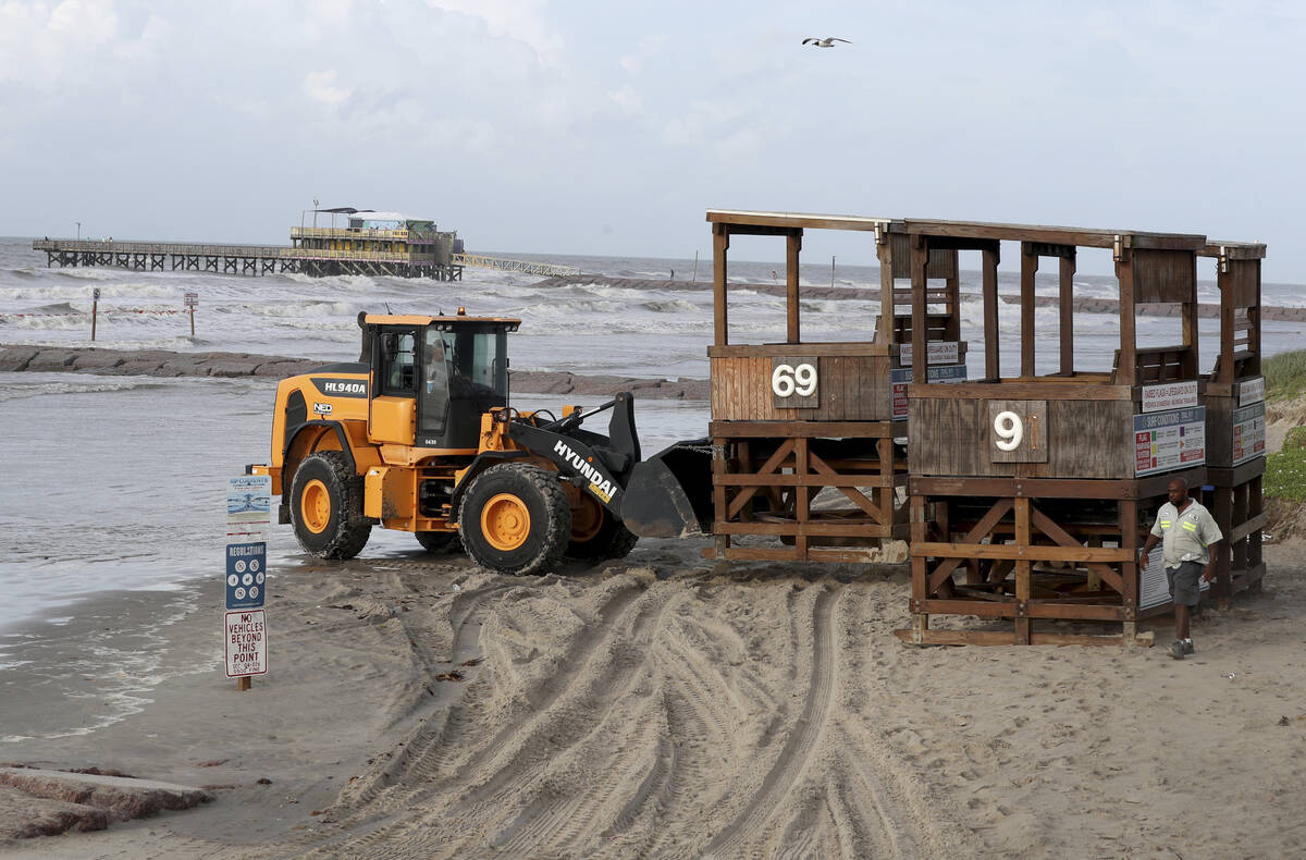 Workers with the Galveston Island Park Board of Trustees remove lifeguard towers from the beach ...