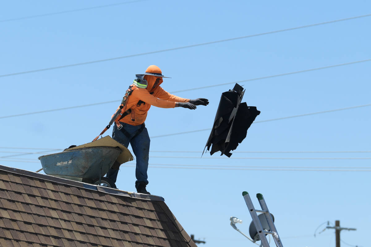 A roofer tosses off old materials while replacing a flat roof on the East side of Las Vegas Mon ...