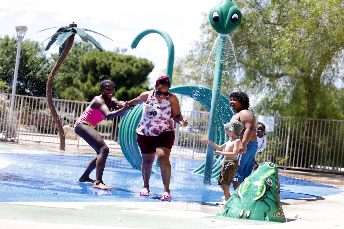 Garrus Williams, 4, center, watches as Markeisha Britton, second left, plays in the splash pad ...